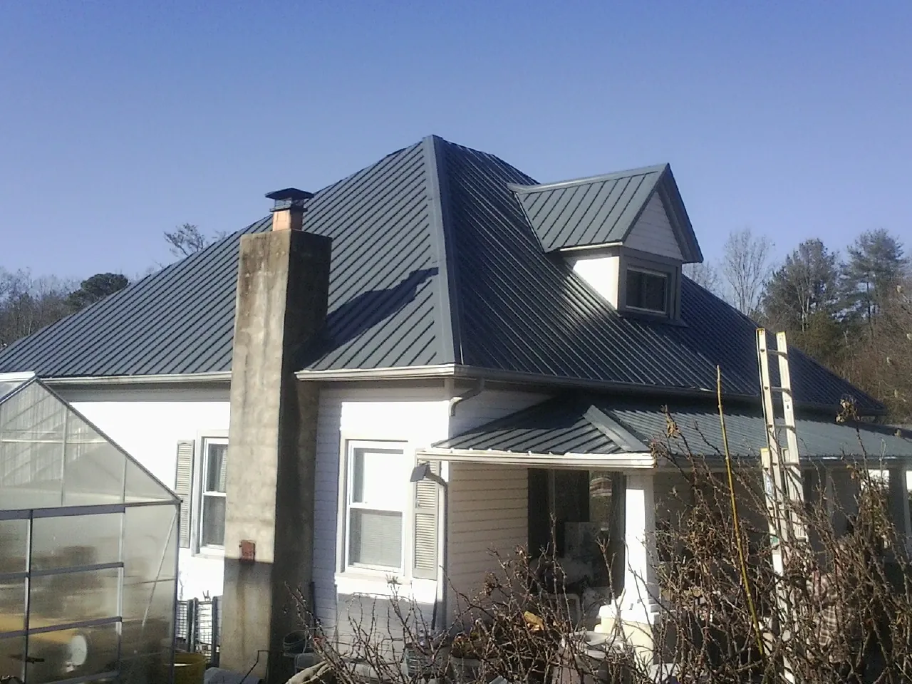 Dark blue standing seam metal roof on a white farmhouse with dormer — Slate & Tile Roof Repair by Roofing Brothers in East Troy