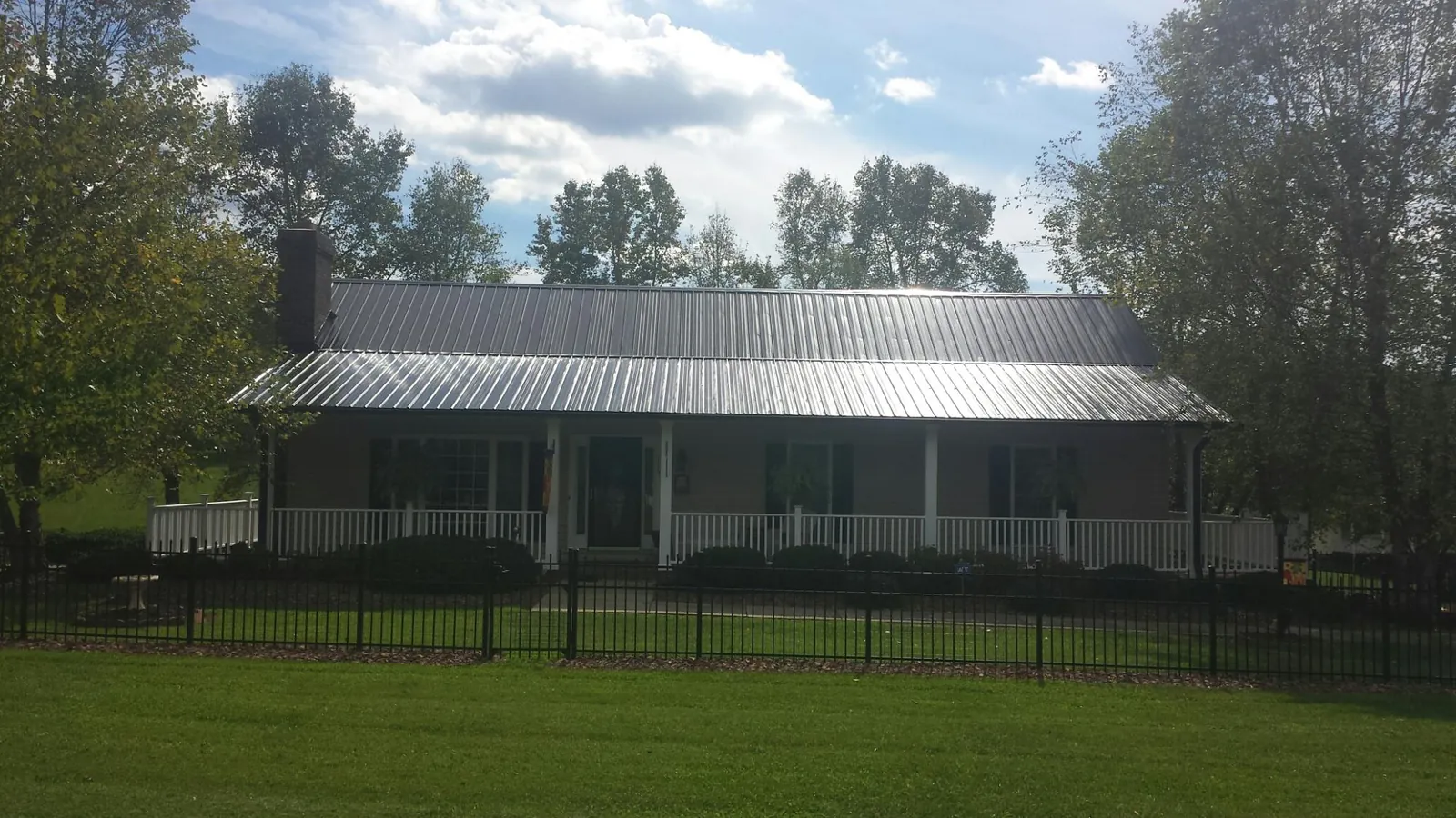 Gray metal roof on a brick ranch with a full width front porch — Gutter Guard Installation work by our crew in East Troy