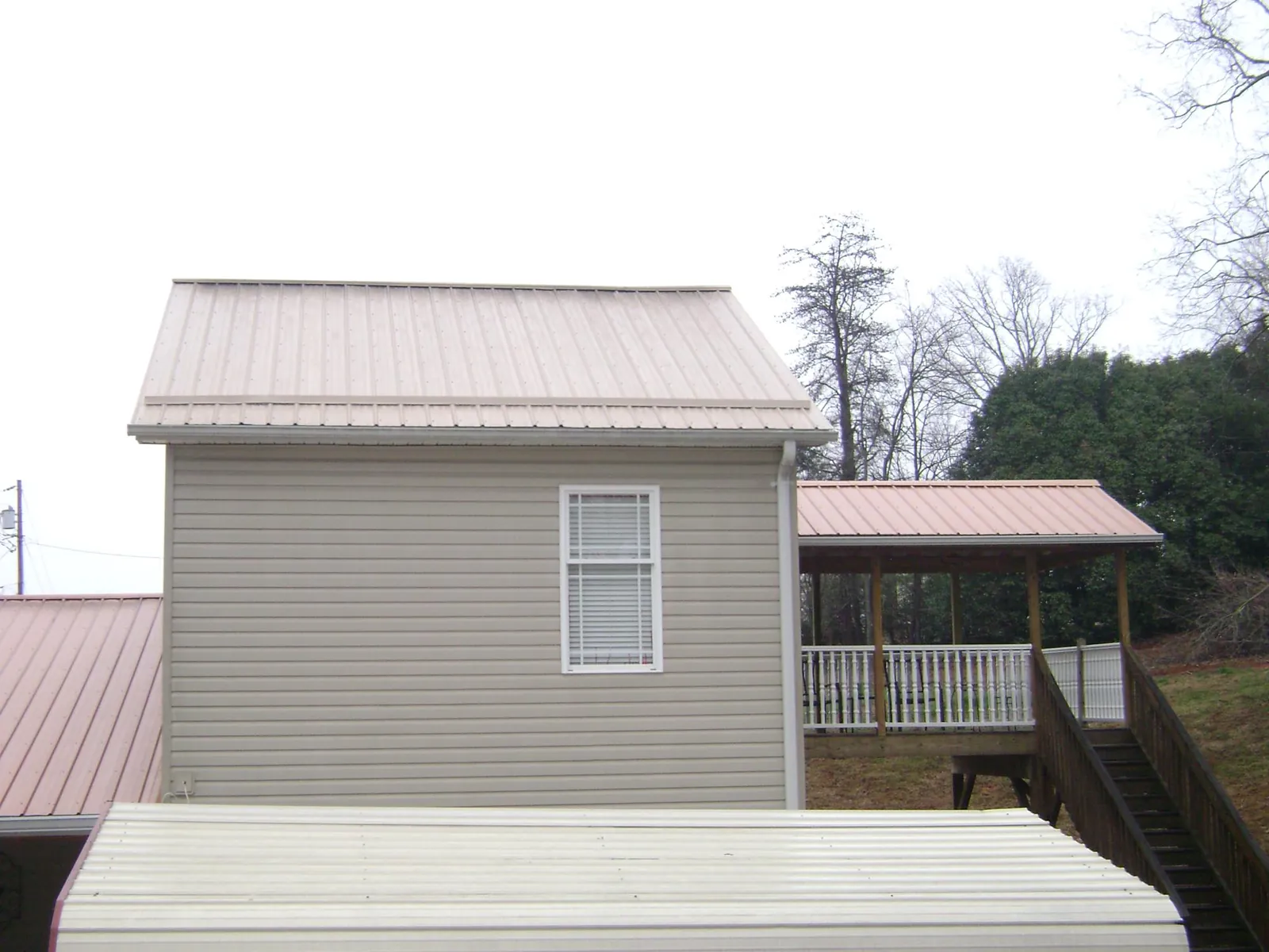 Tan metal roofs on a two story addition and attached porch, from a Roof Replacement job in East Troy